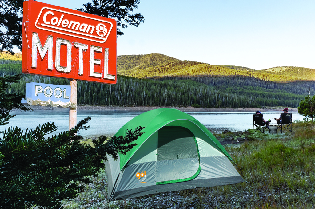 View of Outdoors with mountain, lake and grass in background. Vintage coleman motel sign and coleman tent, 2 people in chairs with a cooler.